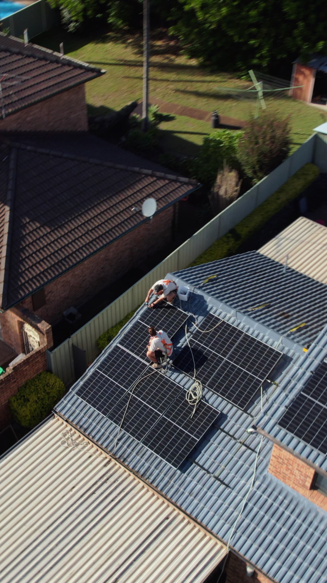 Aerial photo of two installers fitting solar panels on a roof